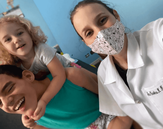 Criança com paralisia cerebral e sua irmã, com a fisioterapeuta, para o texto Sobre o Capacitismo.