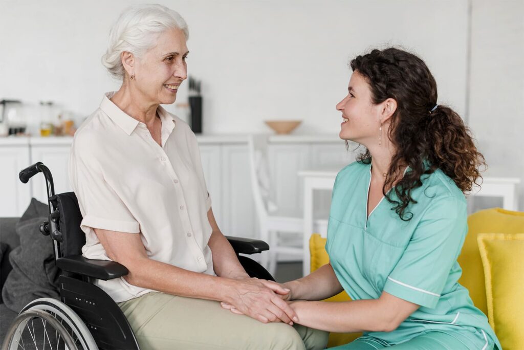 Profissional de saúde e idosa cadeirante ilustrando: Cuidadores podem ganhar até 3 mil mensais