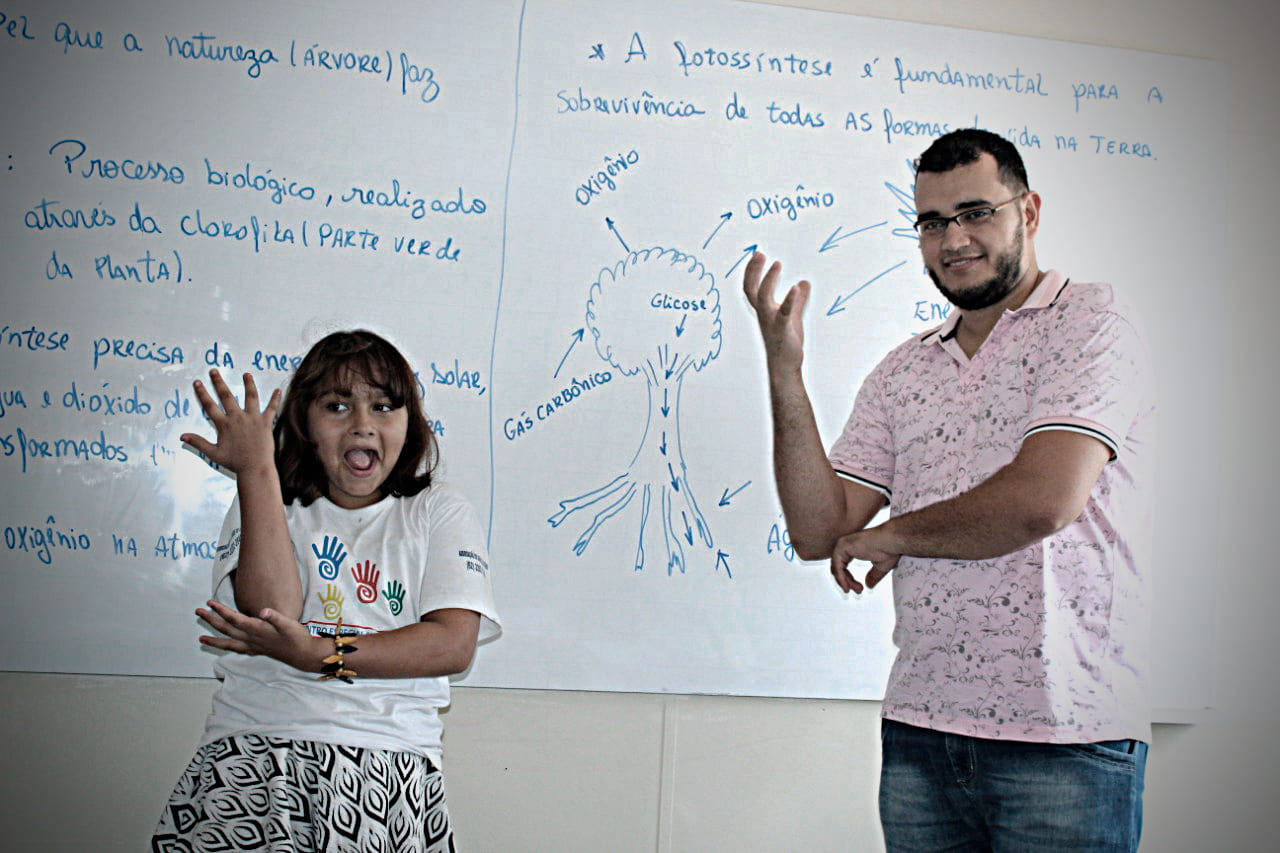 Fotografia com criança e adulto, em sala de aula, com descrição na legenda do texto sobre “Senado debate educação bilíngue para surdos".