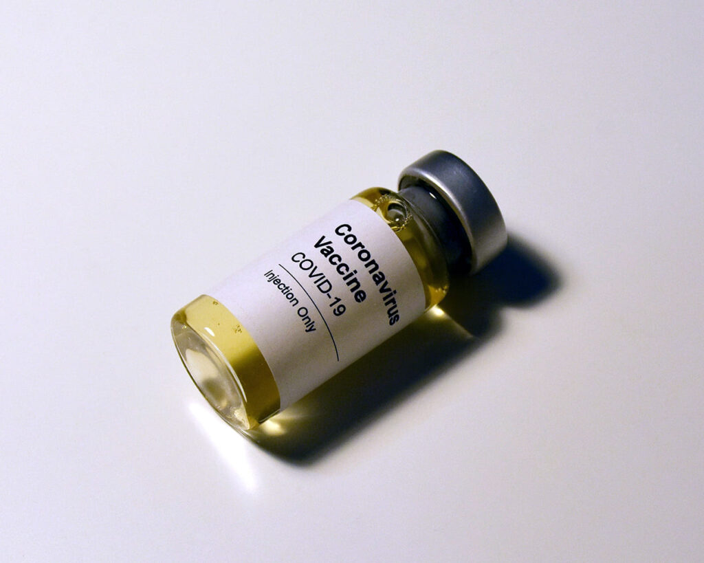 Imagem de um frasco do imunizante deitado sobre superfície plana. No rótulo estão as informações: Coronavírus Vaccine. COVID-19. Injection Only. Ilustrando matéria da xepa da vacina.