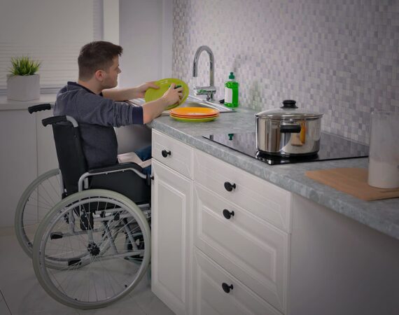 Homem em cadeira de rodas lavando a louça. Descrição na legenda do artigo sobre a importância da acessibilidade em projetos arquitetônicos.