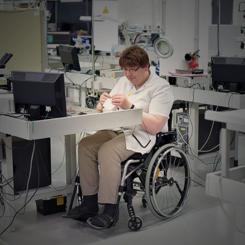 Pessoa em cadeira de rodas montando componentes eletrônicos.