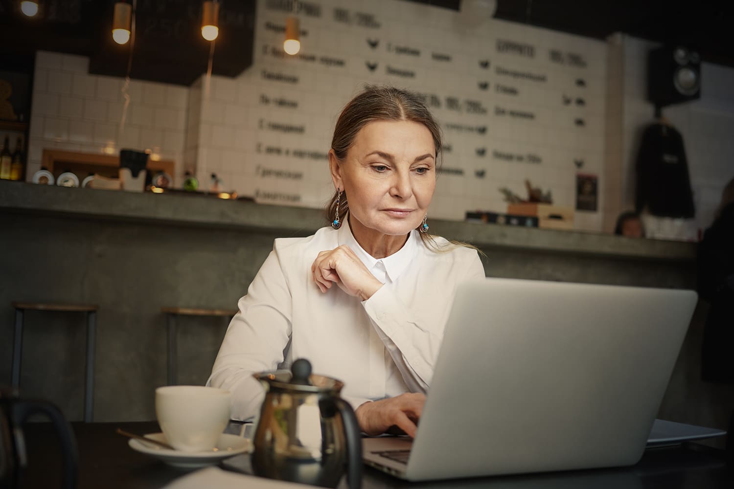 Mulher idosa, de pele branca e cabelos castanhos, usando um computador, para ilustrar "5 motivos para contratar um idoso”.