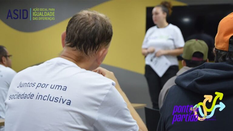 Foto em ambiente interno, com pessoas assistindo palestra. A pessoa em destaque usa camiseta com a frase: Juntos por uma sociedade inclusiva, ilustrando o Projeto da ASID Brasil, chamado Ponto de Partida.