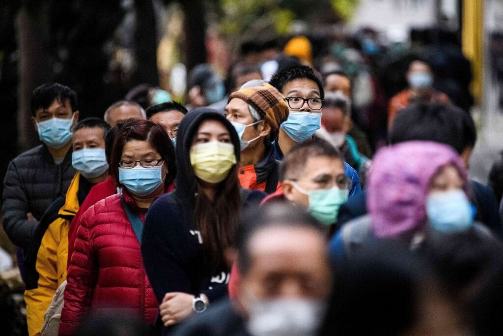 Foto de diversas pessoas usando máscara e caminhando.