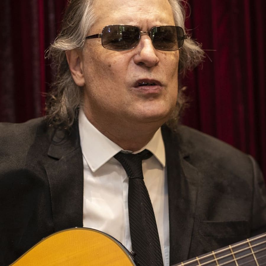 Ricardo Tadeu, com deficiência visual, tocando violão.