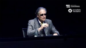 Desembargador cego, Ricardo Tadeu Marques da Fonseca, homem branco de cabelos grisalhos, terno e gravata, e óculos escuros. Discursando no microfone.