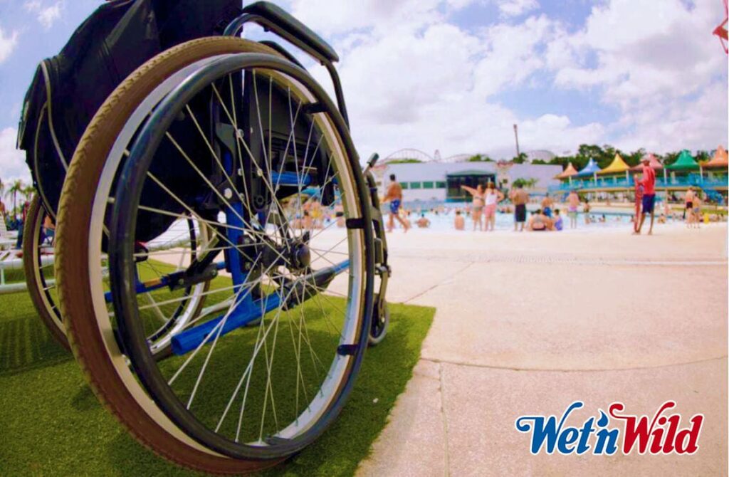 Foto de uma cadeira de rodas, em área externa, com lodo do parque Wet'n Wild.