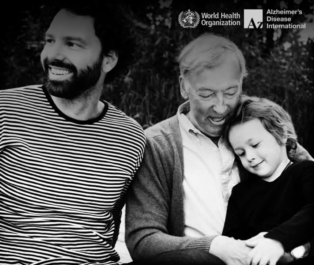 Foto em preto e branco, com três pessoas em momento de descontração familiar. Descrição detalhada na legenda, ilustrando a Comunidade Amiga da Pessoa com demência.