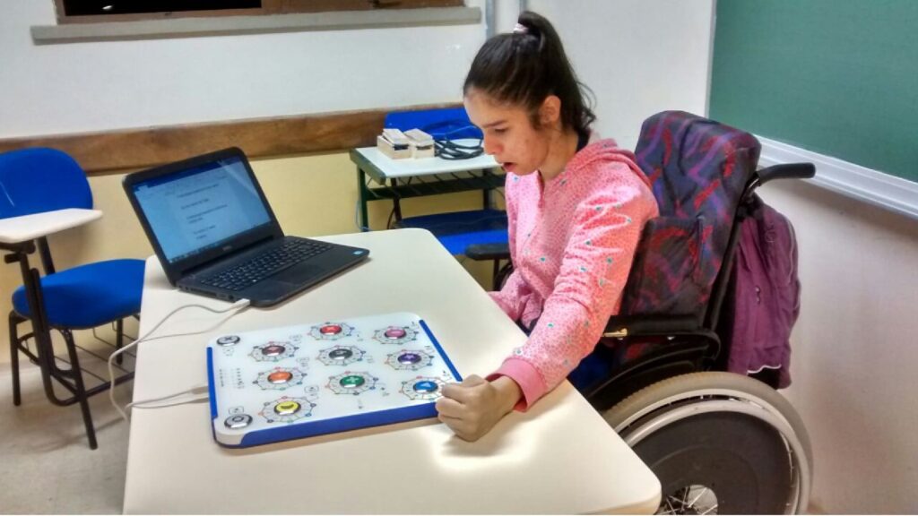 Criança com paralisia cerebral, em cadeira de rodas, utilizando o teclado inteligente multifuncional da startup TiX.
