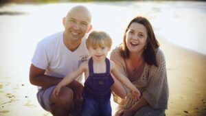 Foto em família com pai, mãe e menino com trissomia do cromossomo 21, notícia “Medicamento para Alzheimer pode melhorar cognição de pessoas com T21.