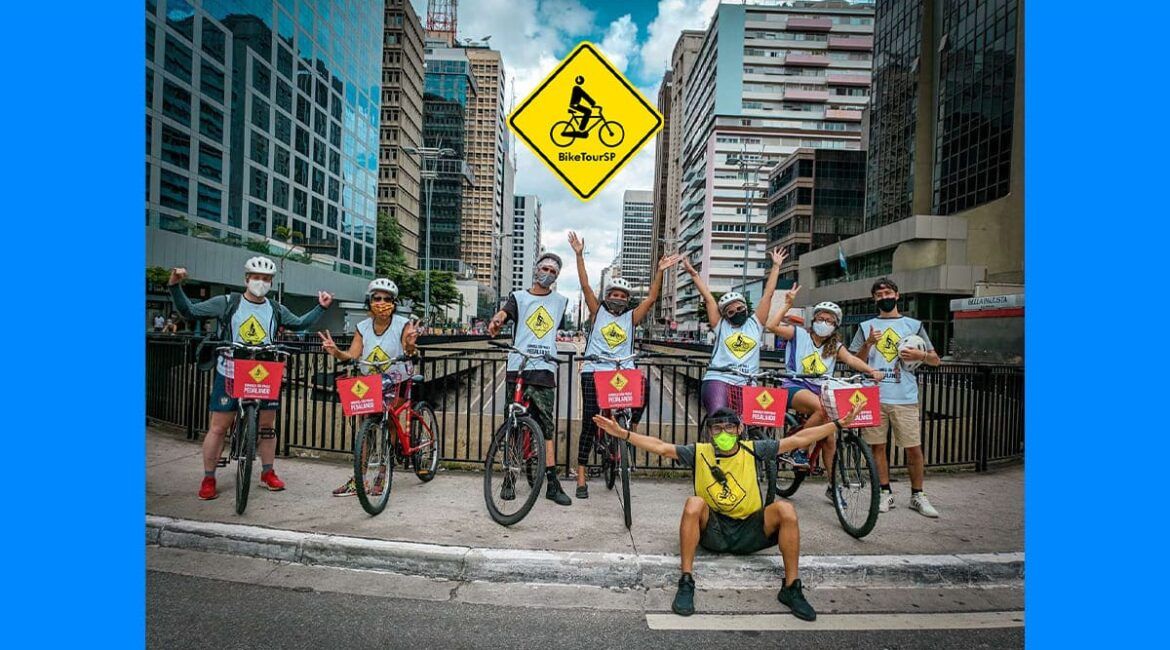 Foto de pessoas com bicicletas, paradas para a foto, na Avenida Paulista, pelo projeto Bike Tour SP, que realiza pedalada em prol do Autismo.
