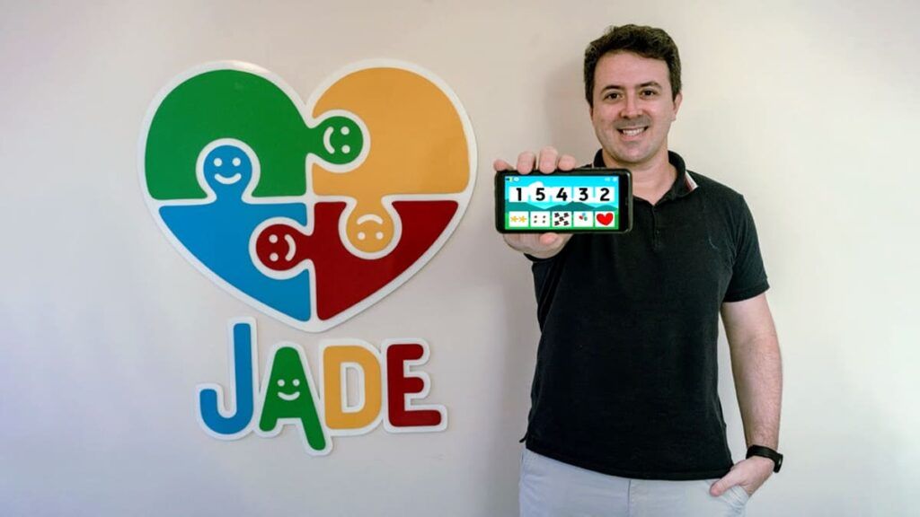 Foto colorida do Ronaldo Cohin, desenvolvedor de Software e CEO da empresa, mostrando o app brasileiro Jade Autism, no celular.