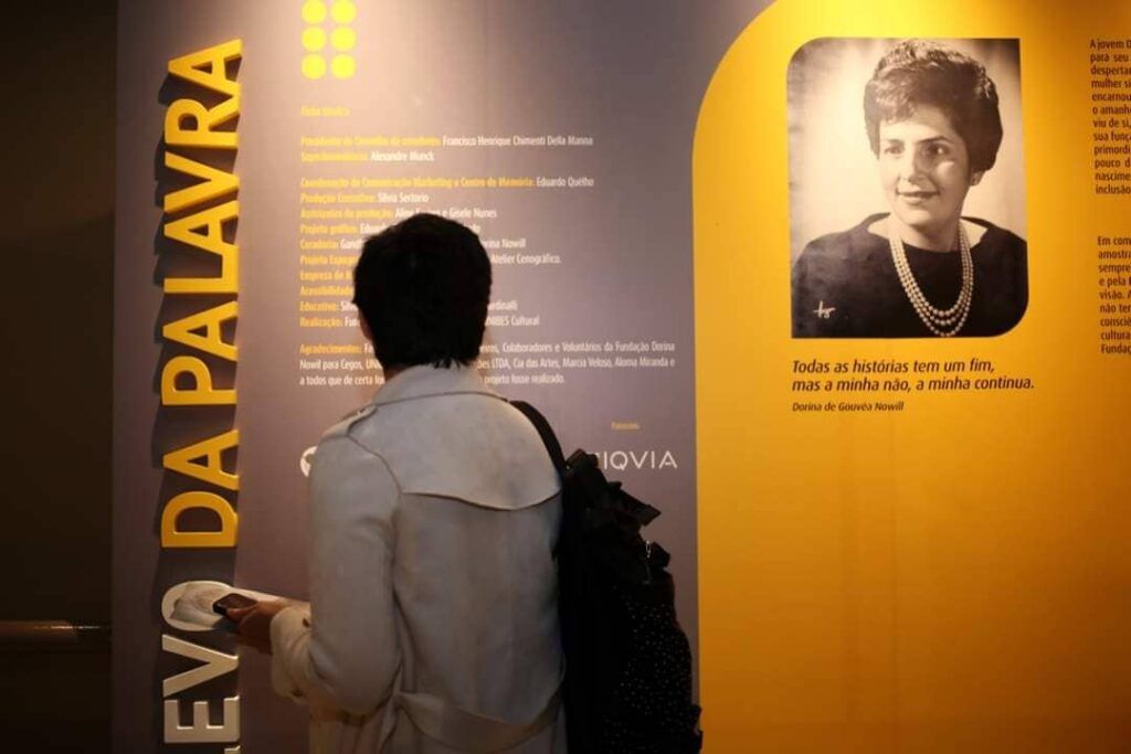 Foto colorida, em ambiente interno, com pessoa de costas em visita à Exposição Relevo da Palavra, na Unibes Cultural.