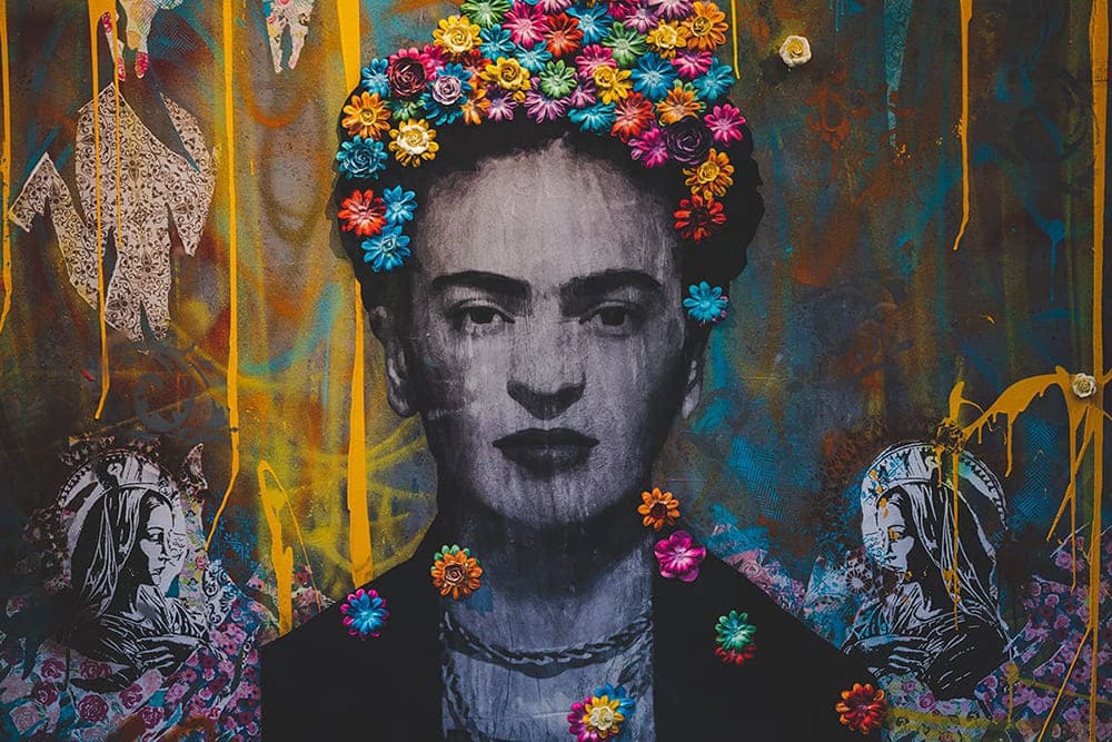Fotografia de muro pichado onde aparece o retrato da pintora mexicana Frida Kahlo, em preto e branco.