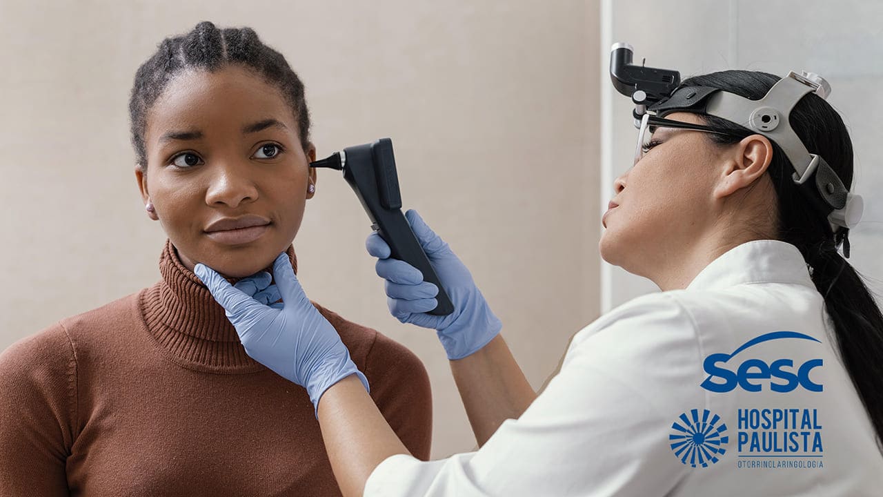 Foto de mulher negra e profissional de saúde realizando triagem auditiva gratuita em SP, no Setembro Azul 2022.