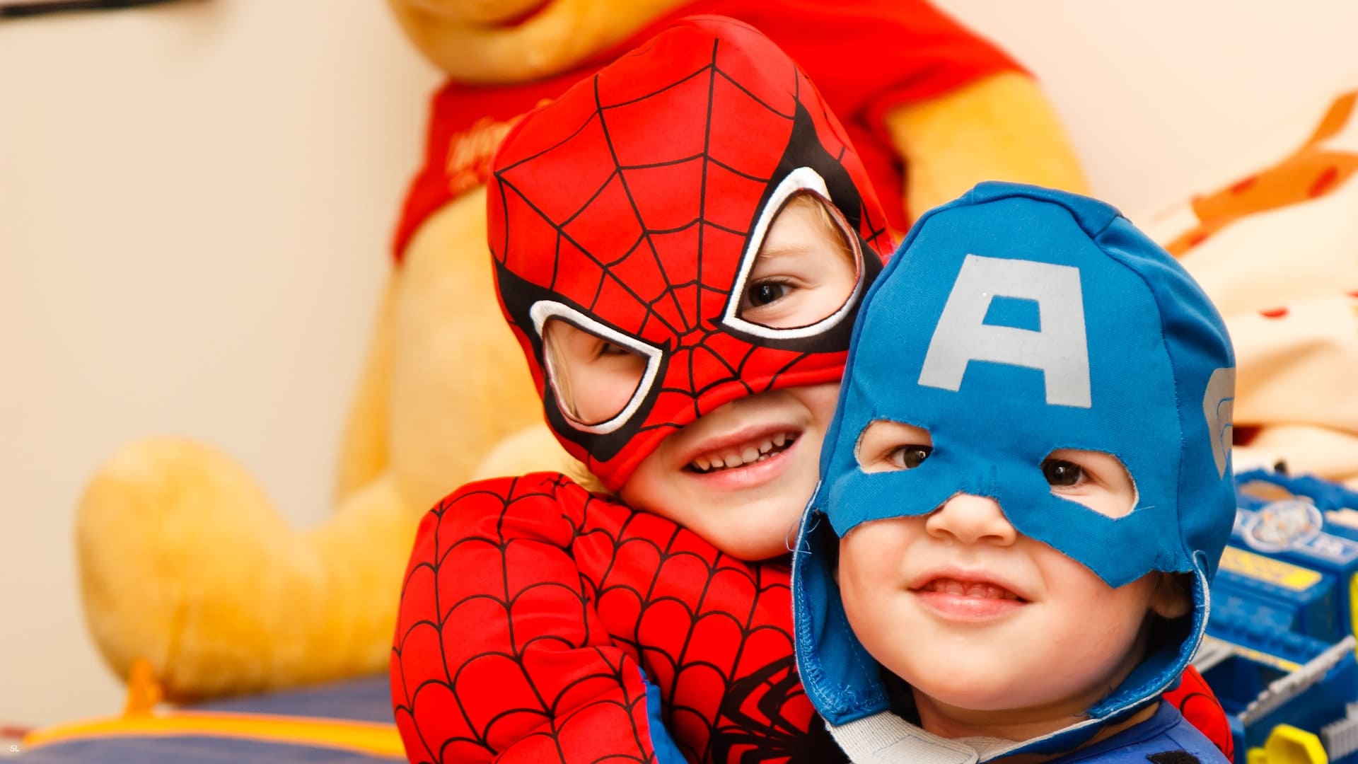 Foto colorida com duas crianças autistas no carnaval, usando fantasia de super-heróis. Uma com fantasia do Homem-Aranha e outra do Capitão América.