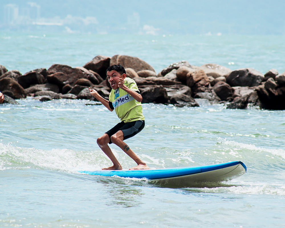 Jovem praticando surf adaptado no Guarujá.