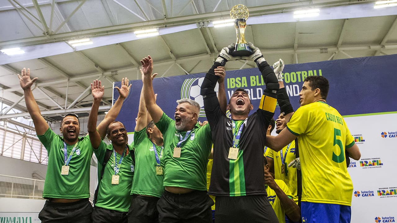 Foto mostra o goleiro do Brasil erguendo o troféu de bicampeão do Grand Prix de futebol de cegos, ao lado de outros jogadores da seleção, comemorando a vitória no Centro de Treinamento Paralímpico.
