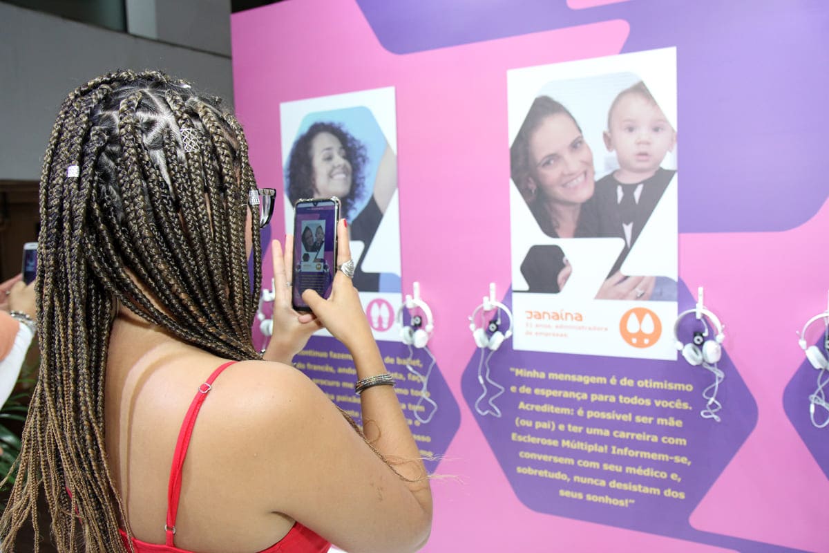 Foto em outra edição da Casa da Esclerose Múltipla retrata mulher interagindo com o celular nas instalações da iniciativa.