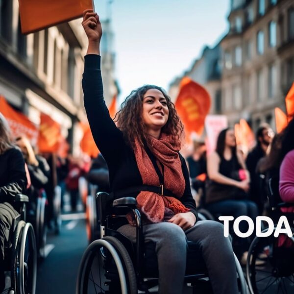 Grupo de mulheres com deficiência em protesto pacífico na rua, bandeiras e cartazes. Símbolo de vênus com punho cerrado e ícone de cadeira de rodas. Logo do Todas in-Rede.