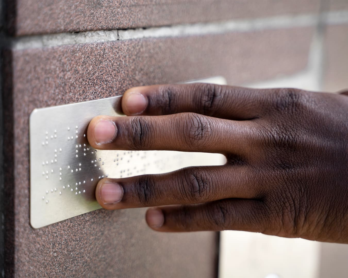 Esta é uma imagem de uma mão pressionando uma placa em braille. Normas de Acessibilidade da ABNT com acesso gratuito: inclusão de pessoas com deficiência.