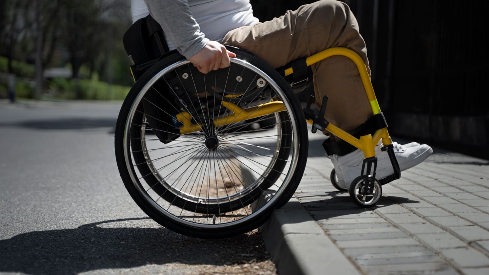 Imagem de pessoa em cadeira de rodas em uma calçada, que não segue as normas de acessibilidade da ABNT.