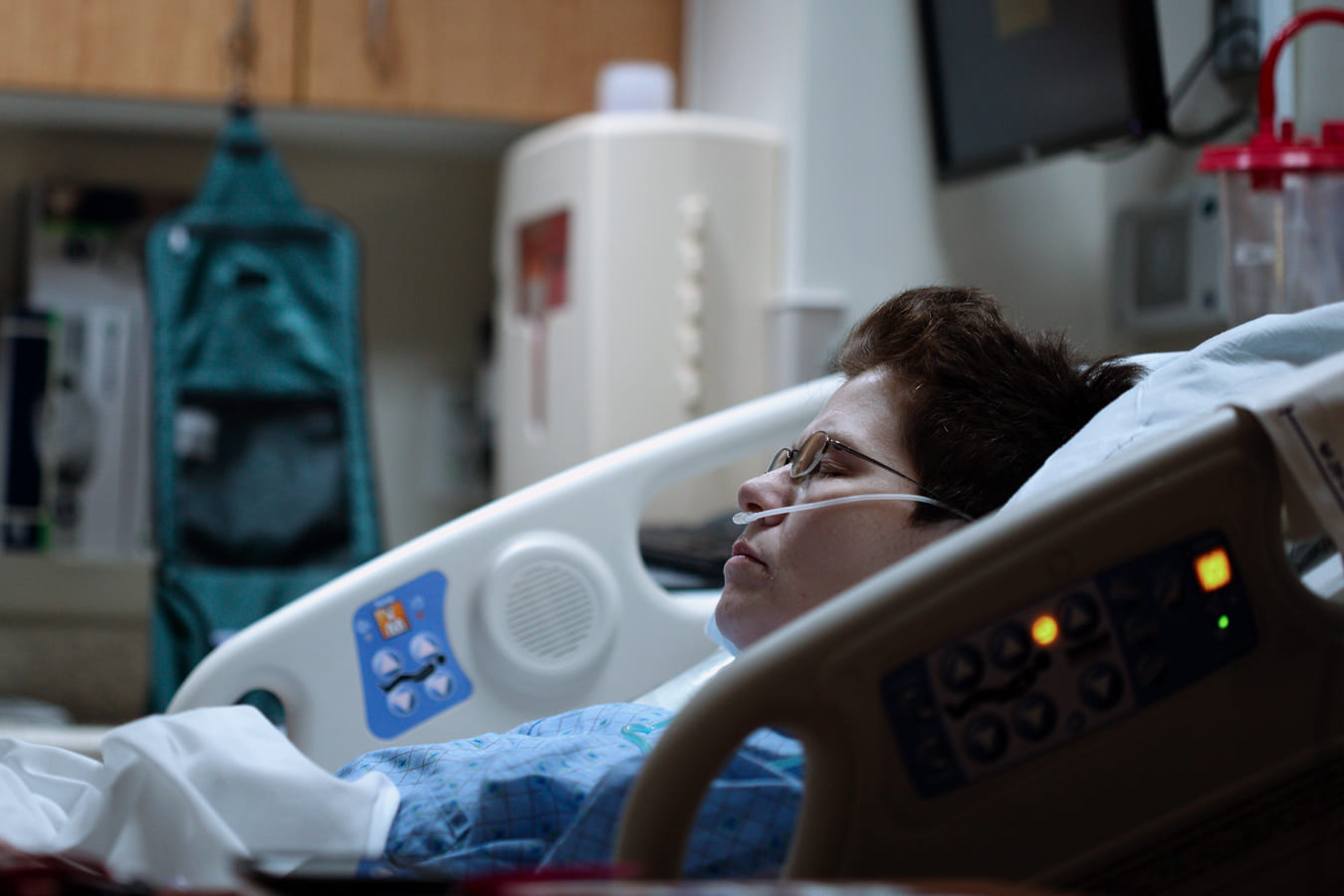 A imagem mostra uma sala de hospital com uma paciente deitada em uma cama.
