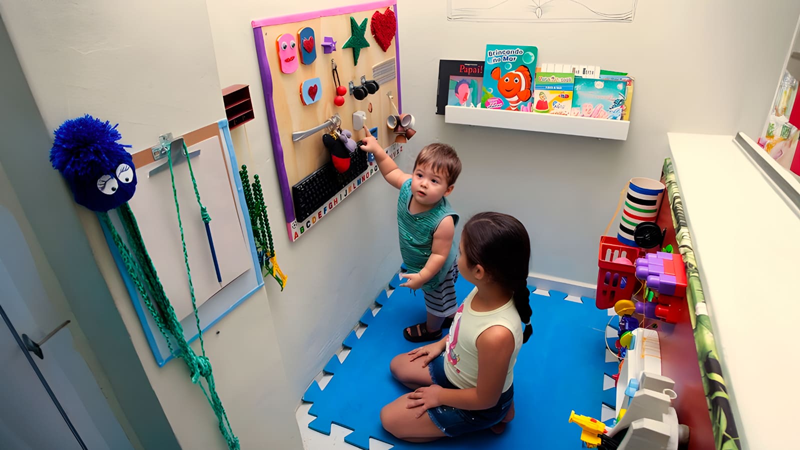 Foto com duas crianças em um quarto transformado em espaço sensorial para o desenvolvimento da criança autista.