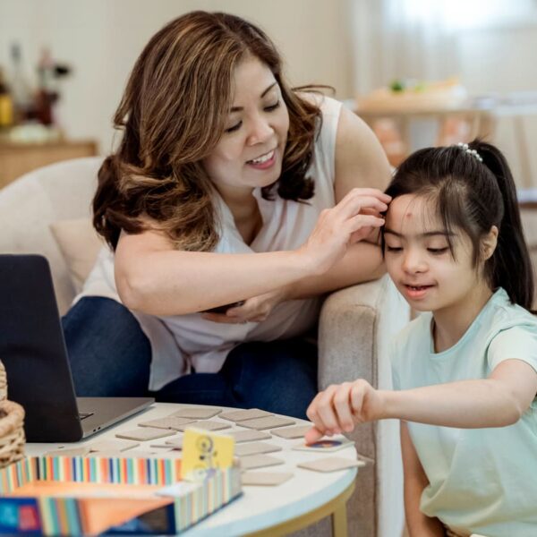 Mãe e filha trabalhando juntas em um quebra-cabeça na sala de estar, ilustrando o desenvolvimento da criança com T21.
