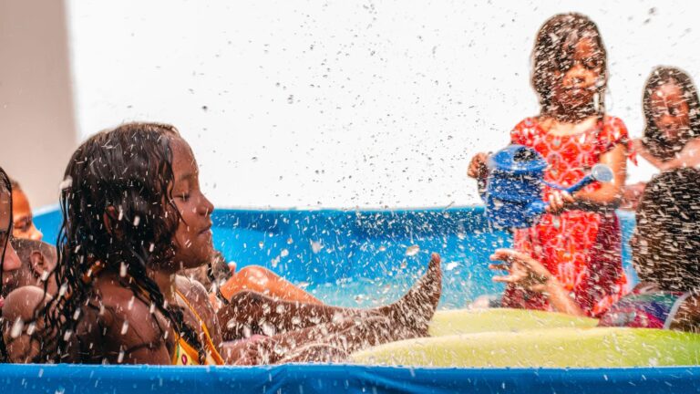 Crianças se divertindo em uma piscina inflável, entre as atividades acessíveis de férias no Galpão Bela Maré, do Bela Verão 2024.