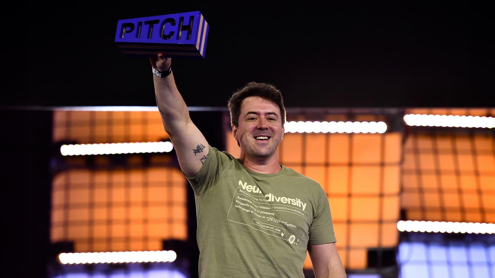 Ronaldo Cohin, CEO da startup Jade Autism segurando uma placa azul com a palavra ‘PITCH’.