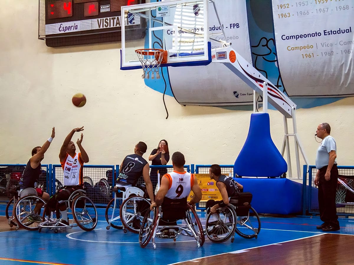 Jogadores de basquete em cadeira de rodas competindo em uma quadra coberta, projeto apoiado pela Lei de Incentivo ao Esporte.
