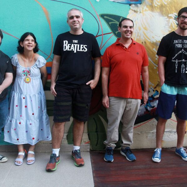Participantes do projeto ‘Moradia Independente’ posando em frente a um mural colorido.