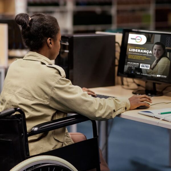 Pessoa em uma cadeira de rodas fazendo inscrição no curso gratuito de liderança para mulheres com deficiência em SP, em um computador.