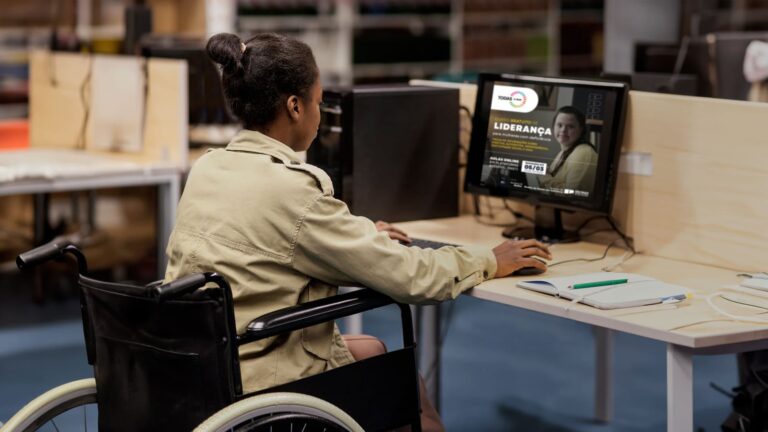 Pessoa em uma cadeira de rodas fazendo inscrição no curso gratuito de liderança para mulheres com deficiência em SP, em um computador.