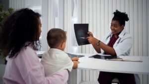 Pediatra mostrando um raio-X para uma criança e seu responsável, na busca da identificação precoce da dislexia.