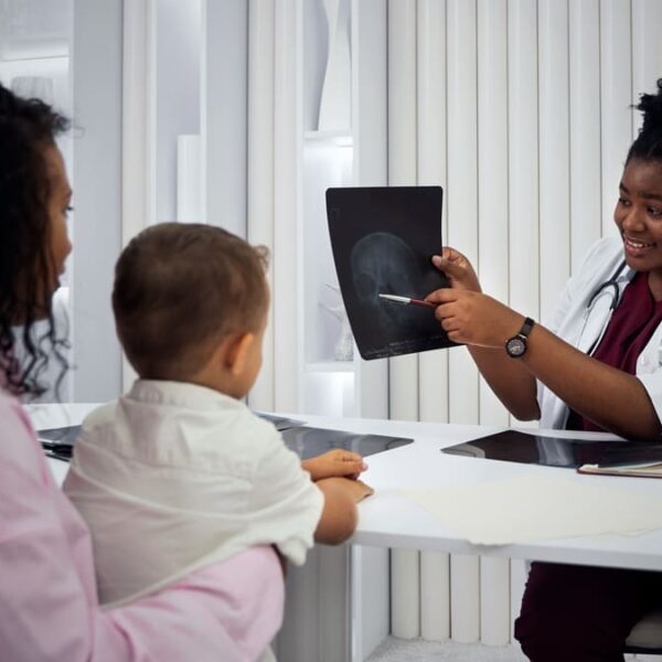Pediatra mostrando um raio-X para uma criança e seu responsável, na busca da identificação precoce da dislexia.