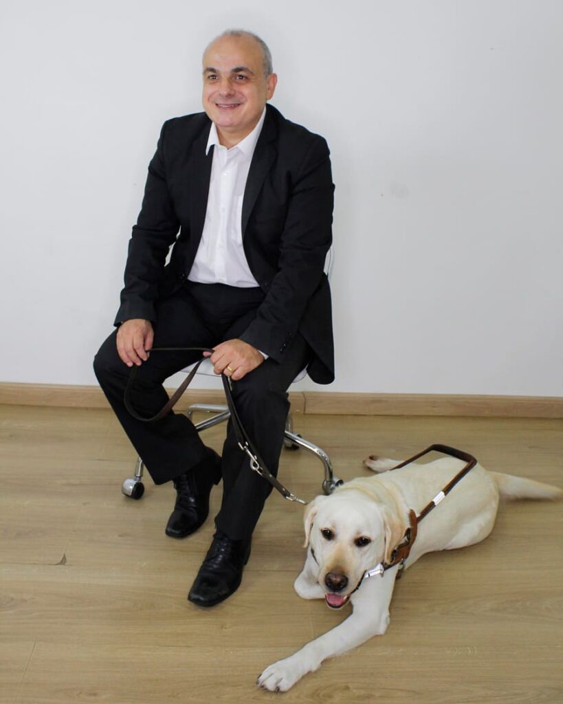 Marcelo Panico, cego, com seu cão-guia, atuando na área de advocacy da Fundação Dorina Nowill para Cegos.