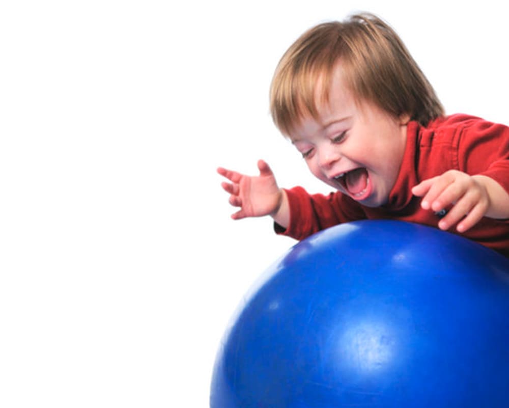 Criança interagindo com uma bola azul grande.