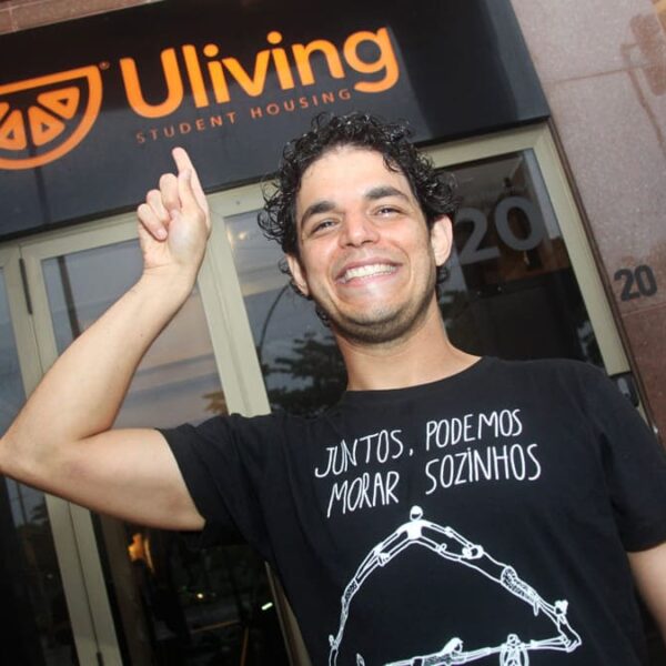 Daniel em frente à Uliving, onde é a primeira moradia independente, vestindo camiseta com mensagem sobre união e independência na moradia: JNG e famílias de São Paulo que avançam na Fase II.