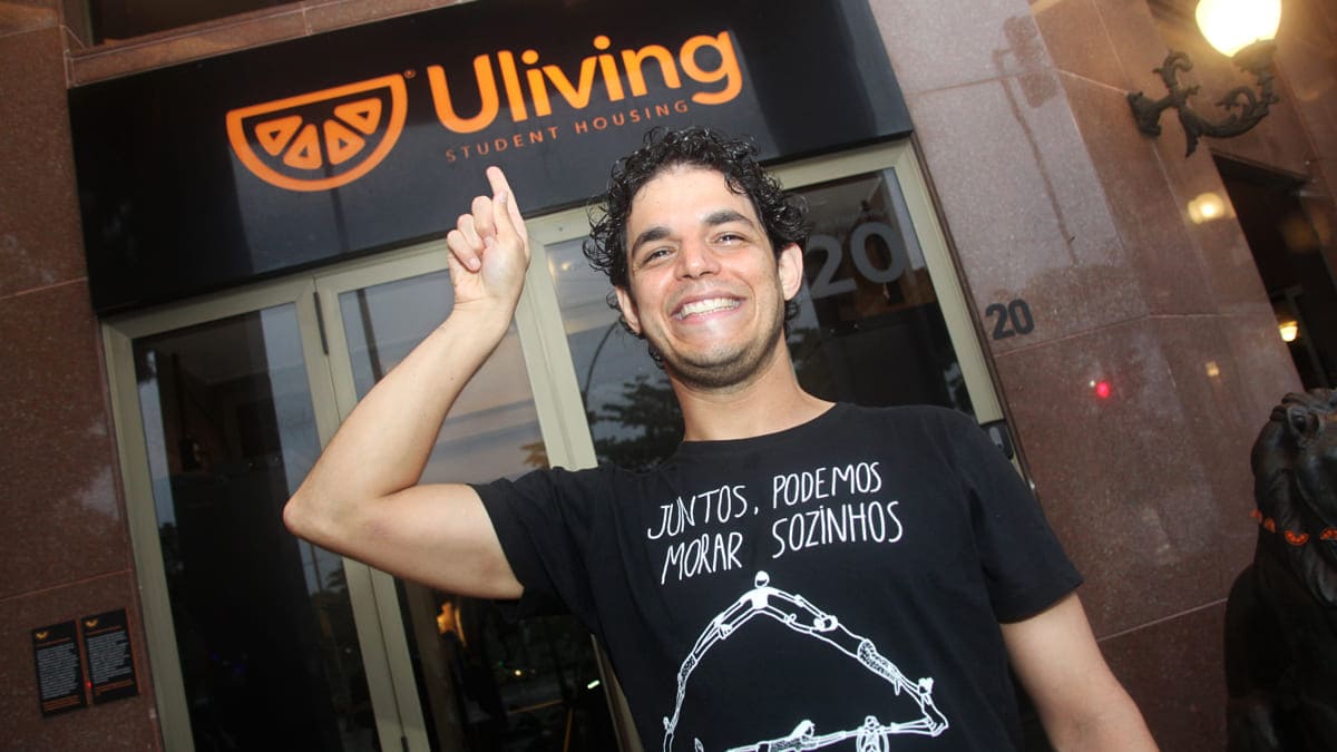 Daniel em frente à Uliving, onde é a primeira moradia independente, vestindo camiseta com mensagem sobre união e independência na moradia: JNG e famílias de São Paulo que avançam na Fase II.