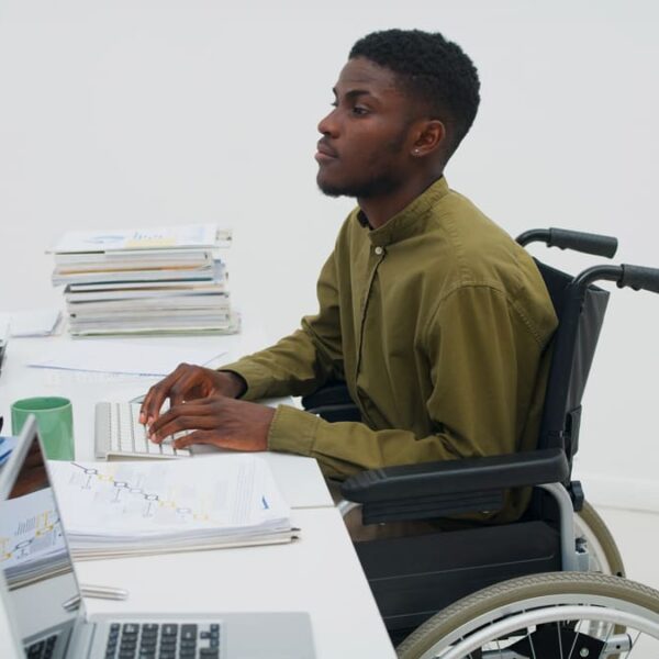 Profissional em cadeira de rodas engajado no trabalho de escritório, ilustrando as 10 vagas de emprego e inclusão no ambiente profissional.