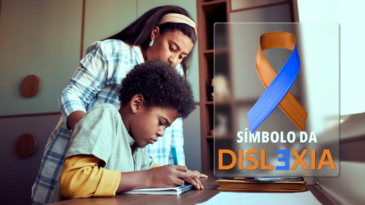 Imagem de um laço azul e laranja sobreposta às palavras Símbolo da Dislexia. Ao fundo, uma pessoa adulta apoia uma criança que está estudando.