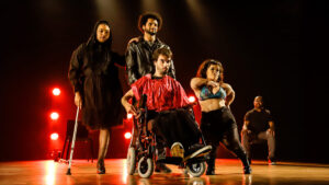 Cinco pessoas em um palco iluminado apresentando o espetáculo ‘Meu Corpo Está Aqui’, uma das atrações da Mostra de Teatro do Presença Festival 2024.