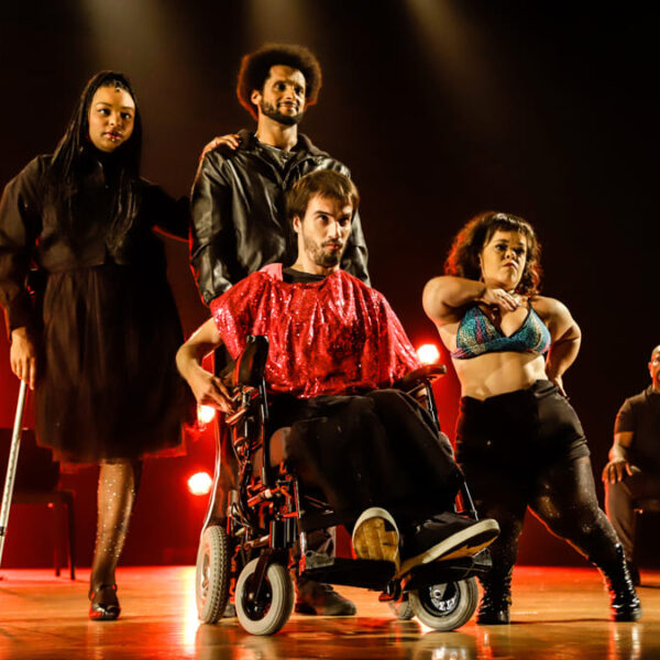 Cinco pessoas em um palco iluminado apresentando o espetáculo ‘Meu Corpo Está Aqui’, uma das atrações da Mostra de Teatro do Presença Festival 2024.