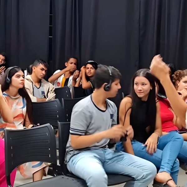 Grupo de pessoas participando do curso online de audiodescrição para cinema, com algumas usando fones de ouvido, enquanto interagem com a instrutora Bell Machado.