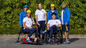 Seis atletas da delegação brasileira, incluindo quatro mulheres e dois homens, posam ao ar livre, usando uniforme oficial e sandálias Havaianas inclusivas.