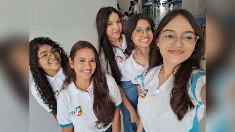 Cinco jovens estudantes posam juntas, vestindo uniformes do SESI, representando um projeto de óculos inteligentes para pessoas com deficiência visual, vencedor do Inova Jovem 2024.