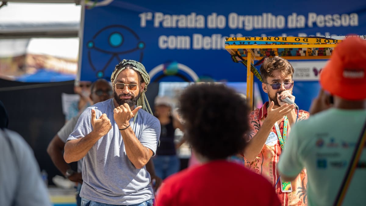 Intérprete de Libras traduz discurso durante a 1ª Parada do Orgulho PCD de Salvador, promovendo acessibilidade para a comunidade surda.